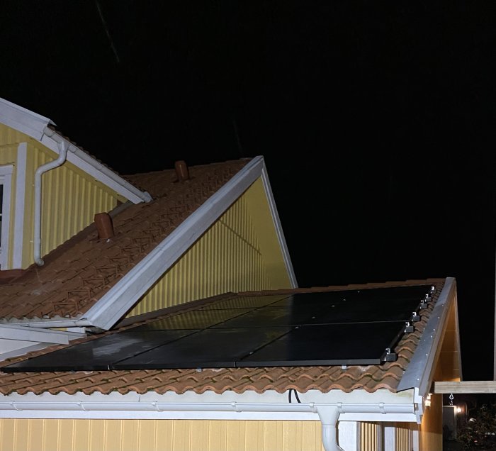 Solpaneler installerade på taket av ett hus under kvällstid.