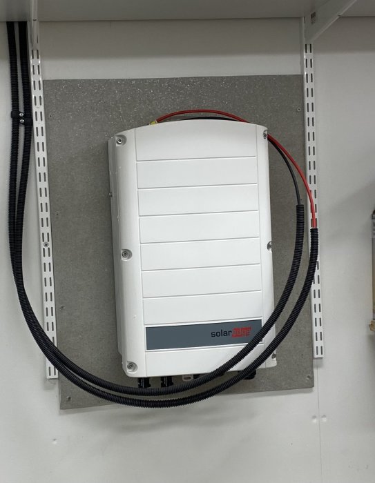 Solenergiinverter monterad på vägg med anslutna kablar redo för elektrikerinstallation.