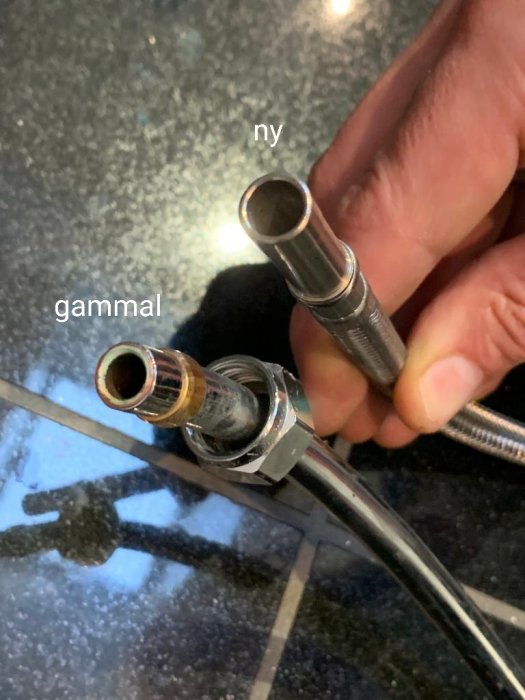 Hand som jämför äldre och nyare vattenanslutningar till blandare med etiketter "gammal" och "ny".