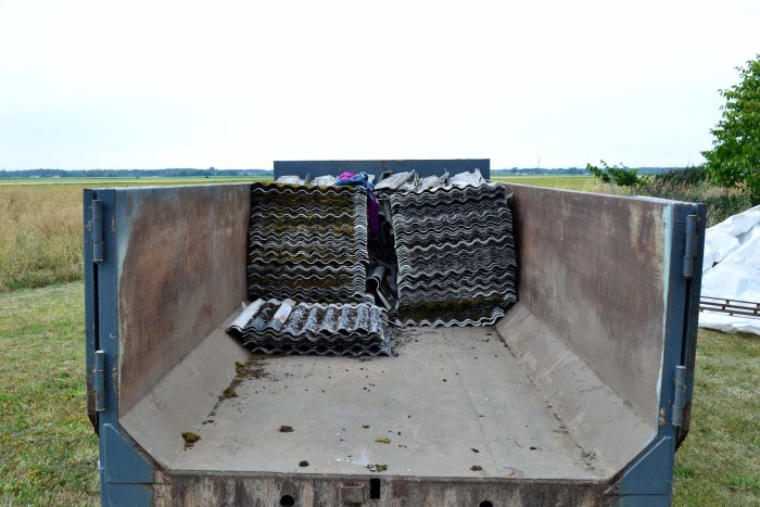 Tom container med gamla svarta och gråa takpannor staplade i bakänden.