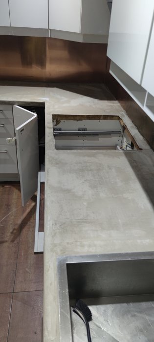 En köksbänk mitt i renovering med ett lager betongliknande microcement ovanpå ekskivan.