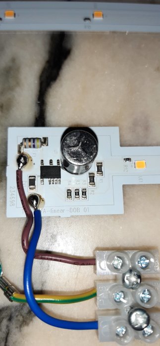 En LED-belysningsdriver med elektroniska komponenter och anslutna kablar, på väg att modifieras för dimning.