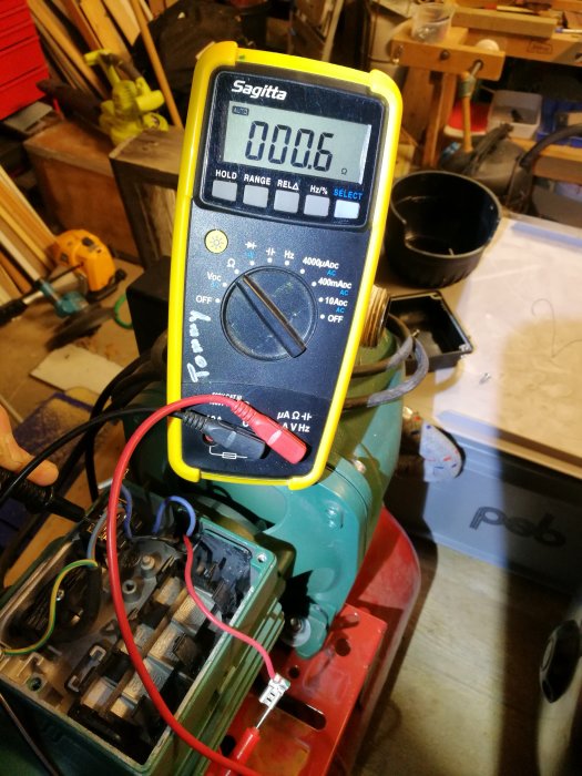 Multimeter visar 0,6 Ohm på en pumpmotor i en verkstadsmiljö.