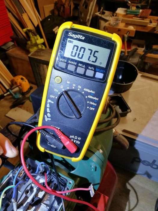 Multimeter visar 7,5 Ohm ansluten till en pumpmotor i en verkstadsmiljö.