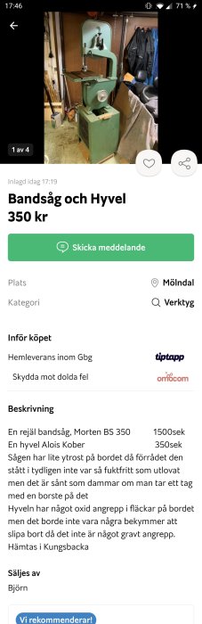 Stående bandsåg i ett garage, grönt stativ med en tillhörande träsågningsbänk, synligt använd och något dammig.