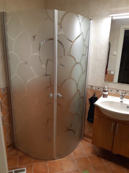 Nyinstallerad rundad 90x90 duschhörna med dekorativa glas i ett kaklat badrum under renovering.