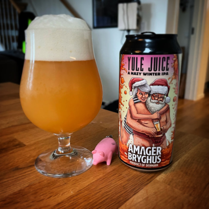 Ett glas öl med jul-IPA från Amager Bryghus och en liten rosa grisfigur på ett bord.