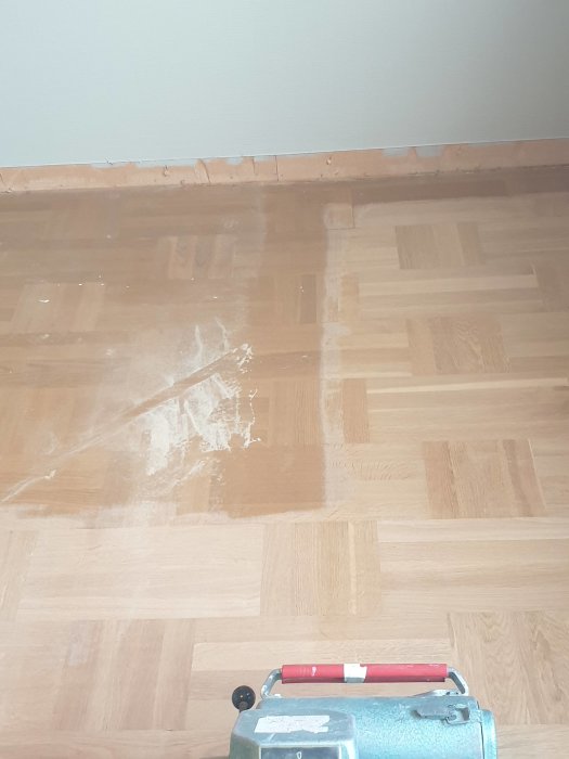 Golvslipmaskin på ett parkettgolv med synlig slipningsskillnad.