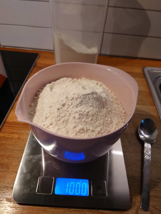 En skål med mjöl väger exakt 1000 gram på en digital köksvåg, förberedelse för pizzabak.