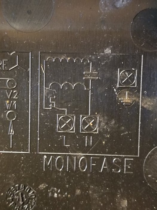 Elektriskt schema ingraverat på metallplatta med texten "MONOFASE" och olika symboler.