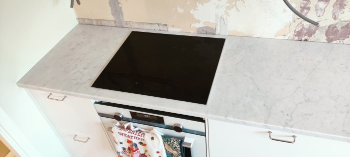 Marble countertop with built-in cooktop and unfinished wall in the background.