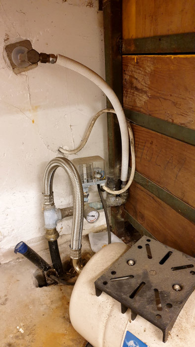 Vattenbrunnsteknik i garage med slangar, tryckkärl och tekniklåda, anslutet till vattenutkastare.