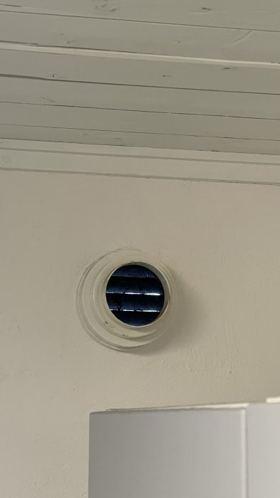 Ventilhål i vitmålad vägg ovanför en vit yta, avsett för ventilation i hus.