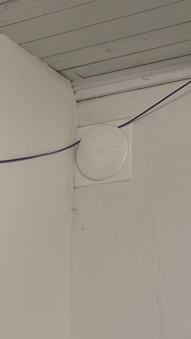 Förseglat ventilationshål i vit vägg med synlig elkabel.