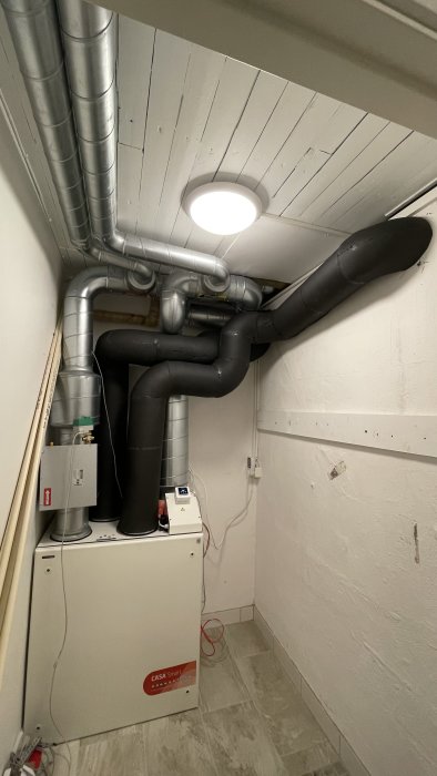 Nytt installerat FTX-ventilationssystem i vitmålad källare med synliga rör och enheter.