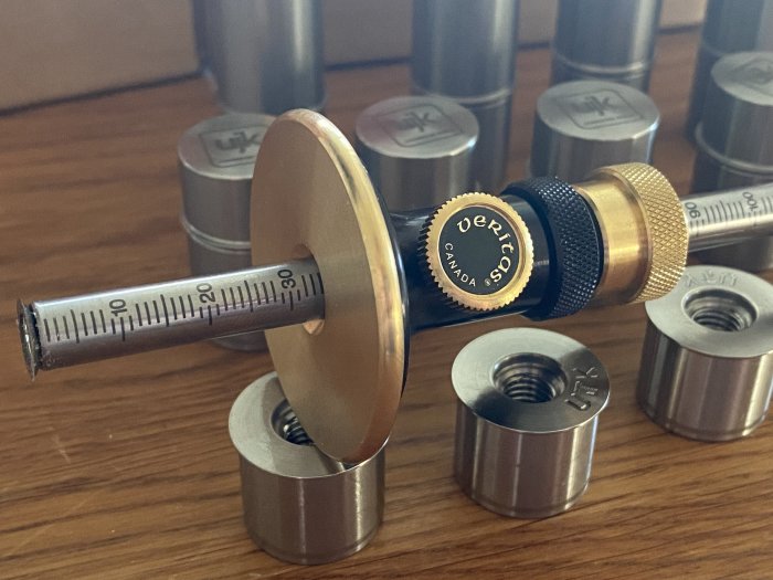 En Samling av metallmöbleringsdowels och en inställbar borr på ett träbord.