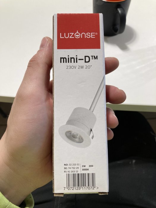 Hand håller en Luzzense mini-D fönstersmygspotlampa för 230V, förpackningen visar produkten och specifikationer.