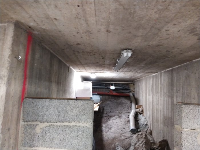 Renoveringsarbete i källare med avfuktare, ventilationsslang nära trappsteg och murade väggar.
