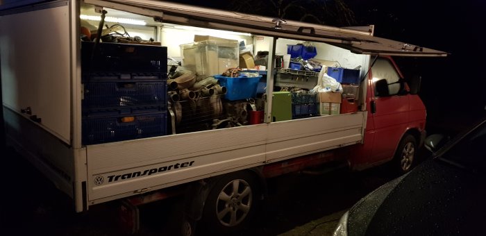 Volkswagen Transporter-pickup fullastad med verktyg och prylar under kvällsbelysning.