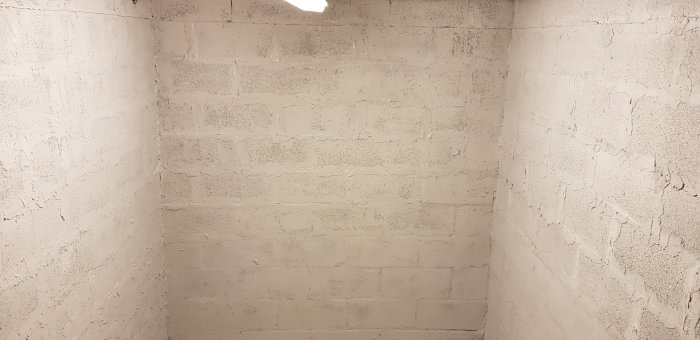 Nyrenoverat hörn i garage med ny vit färg på grovt putsade betongväggar.