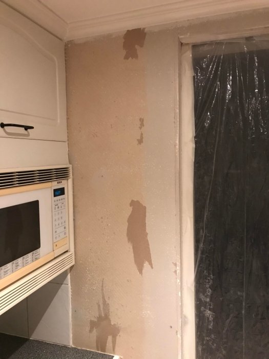 Vägg i behov av renovering med borttagen tapet, synliga skarvar och spackelkladd vid ett fönster.