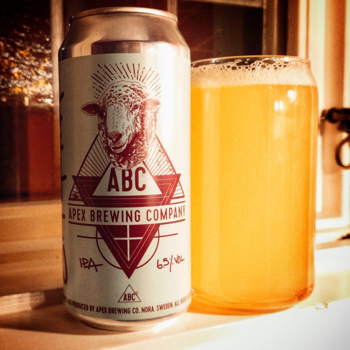 Ölburk med ABC Apex Brewing Company-logotyp och ett glas med oklar orange vätska, troligen öl.
