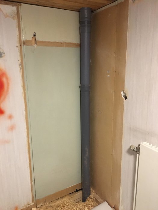 Avloppsrör går längs en öppnad vägg markerad med X, bakom där en garderob revs, under renovering.