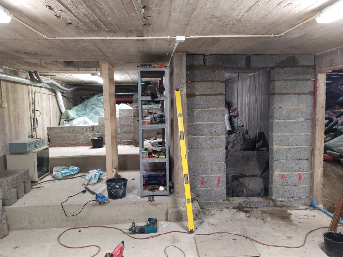 Pågående byggprojekt med minimalistisk formsättning ovanför dörröppning, stabiliserad med två armeringsjärn.