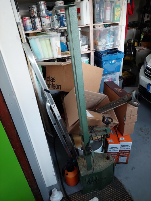 Gammal svarv i en rörig garageverkstad bland lådor och byggmaterial.