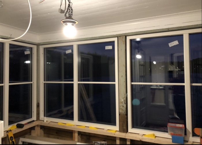 Interiör av uterum med nyligen installerade fönster med klassiska profiler i skymningen.