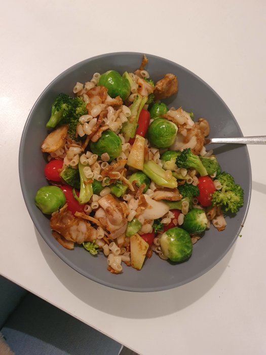 En tallrik med kycklingkebab, brysselkål, broccoli, körsbärstomater och makaroner.