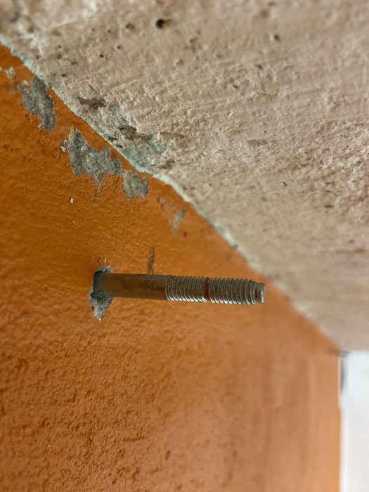 Utskjutande bult med gängad del i en betongvägg under renovering.