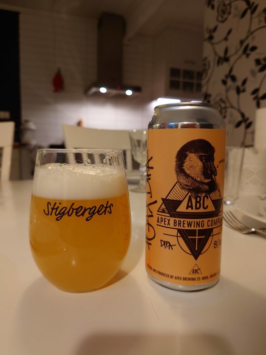 Ölglas märkt "Stigbergets" och burk från "Apex Brewing" på ett köksbord.
