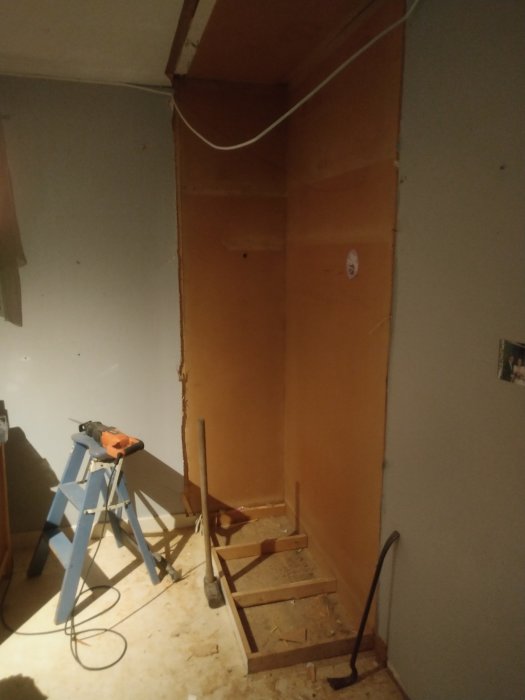 Renoveringsarbete med rivet skåp, osammanhängande tak och förberedelser för tapetsering i ett rum.