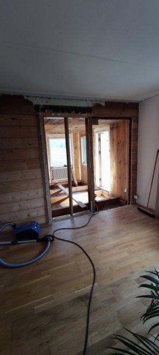 Renoveringsprojekt med vägg som delvis rivits ner, exponerade reglar och trägolv.