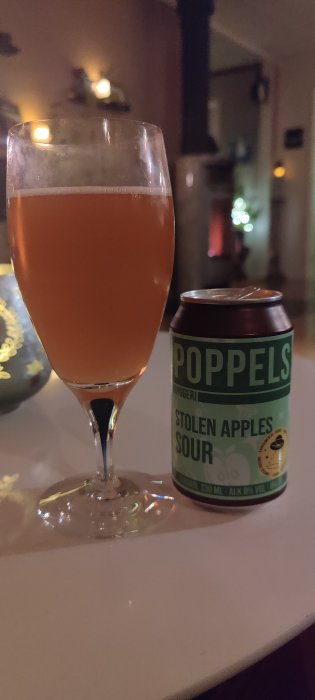 Ett glas med rosa öl bredvid en Poppels burk märkt Stolen Apples Sour.