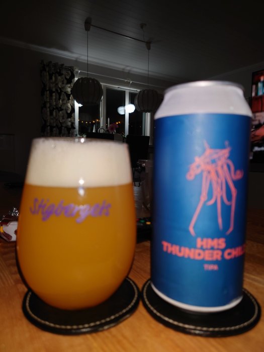 Ölglas med skummad öl bredvid en blå ölburk med texten "HMS Thunder Child TIPA" på en bordsduk.