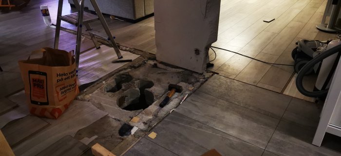 Uppbruten del av ett betonggolv där ventilationsrör tidigare varit placerade, omgivet av verktyg och renoveringsutrustning.
