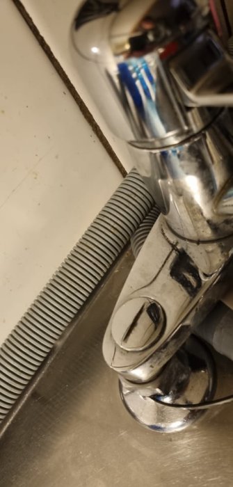 Närbild av en Mora-blandare med fokus på en skruv/plugg i hörnet av en diskbänk.
