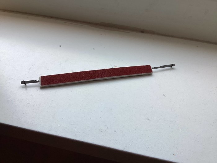 Hemmagjord slipfil med röd slippappersremsa fastsatt på skruv med dubbelhäftande tejp.