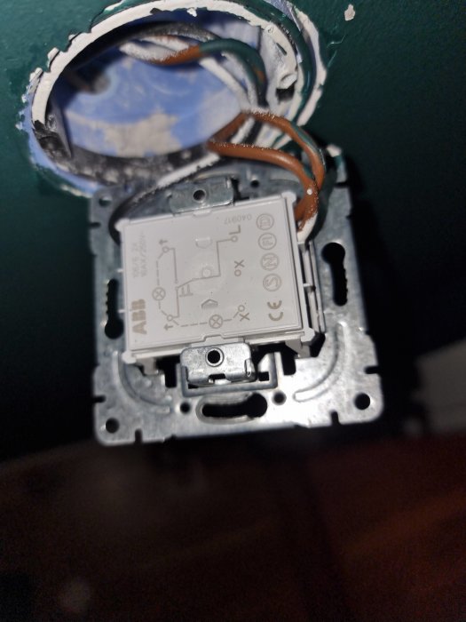 Öppen väggströmbrytare med exponerade kablar och en Hue wall switch modul delvis installerad.