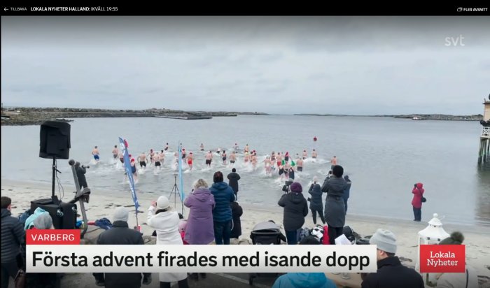 Personer tar ett vinterbad i havet i Varberg medan åskådare tittar på.