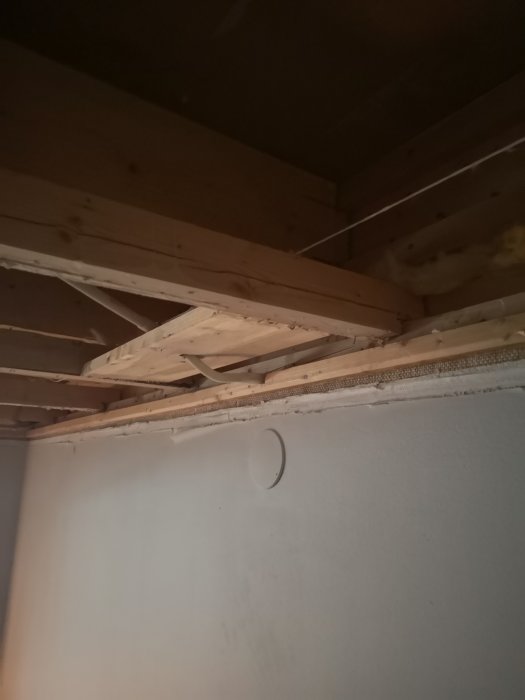 Eldragningsrör under träreglar i taket med synlig utmaning för installation av glespanel.