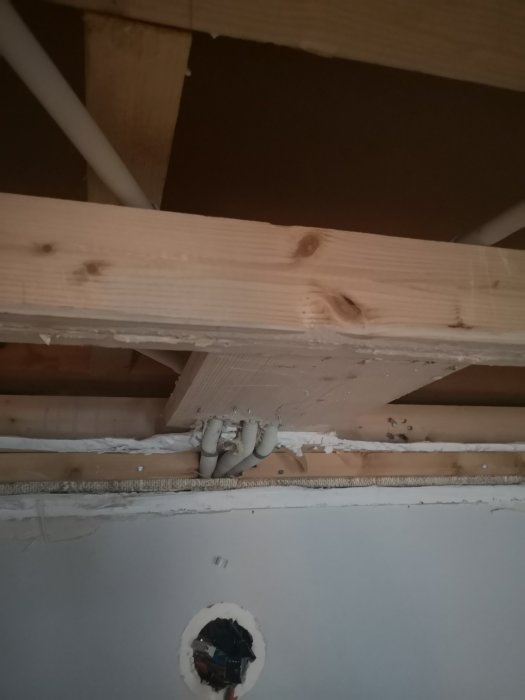 Eldragningar på en vägg under en träregel, indikerar problem med installationshöjd för nästa lager väggbeklädnad.