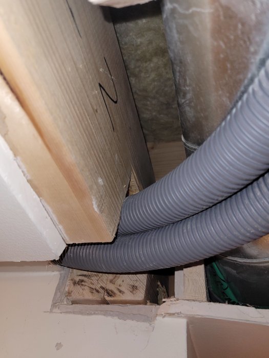 Ca 10x10 cm avsnitt av bärande balk med insågat hål för installation av golvvärmerör.