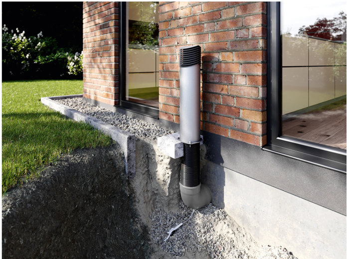 Ventilationstorn för köksfläkt installerat vid husgrund med utlopp nära fönster och tegelvägg.