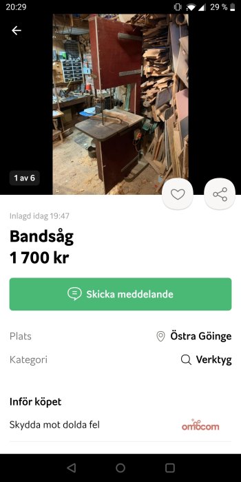 En använd bandsåg i en verkstad med träarbetsverktyg och material staplade i bakgrunden.