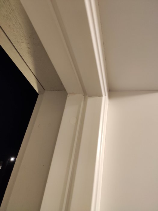 Utsnitt av en dörrkarm utan tätningslister i en urfräsning, vilket indikerar behov av isolering.