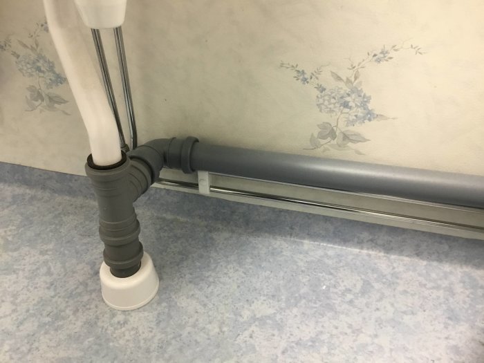 Grått 50 mm avloppsrör installerat som spilltratt med vattenlås i ett badrum.