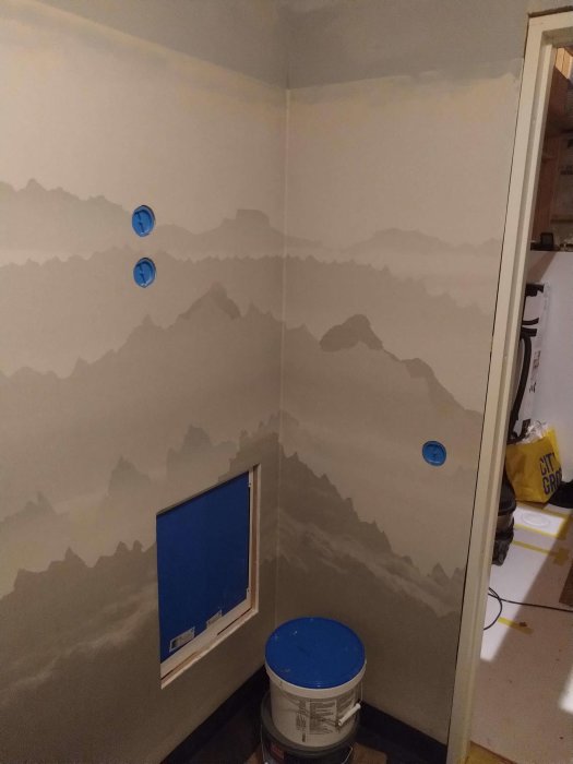 Renoverat badrum med bergsinspirerad våtrumsmatta på väggarna, förberett för elinstallationer.